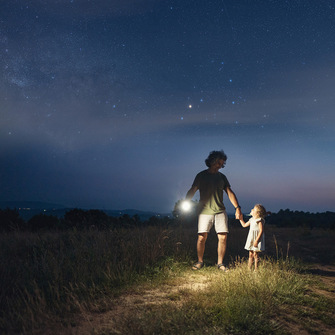 a man and child holding hands with a flashlight
